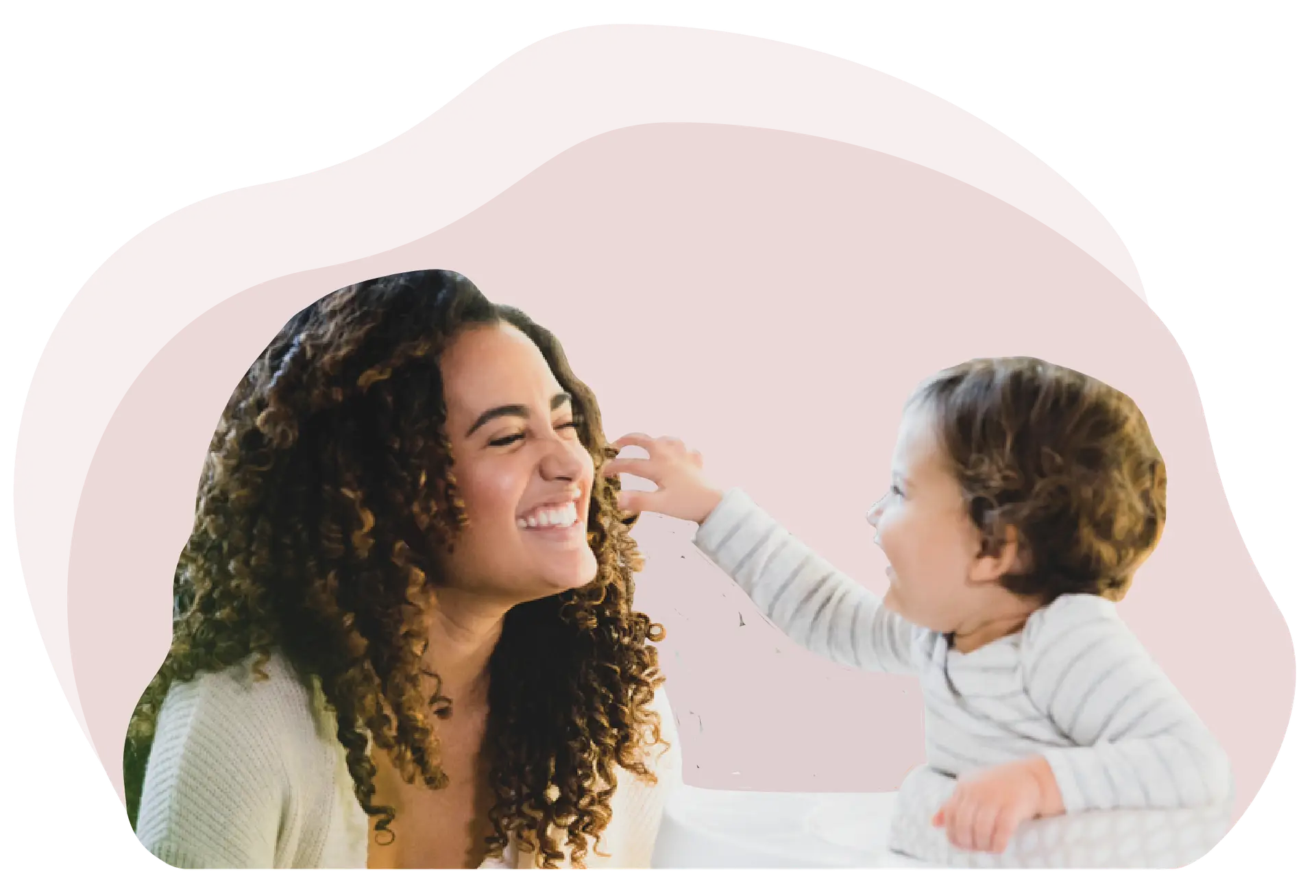 A baby is reaching for his nanny and the nanny is grinning with her eyes closed while facing the baby